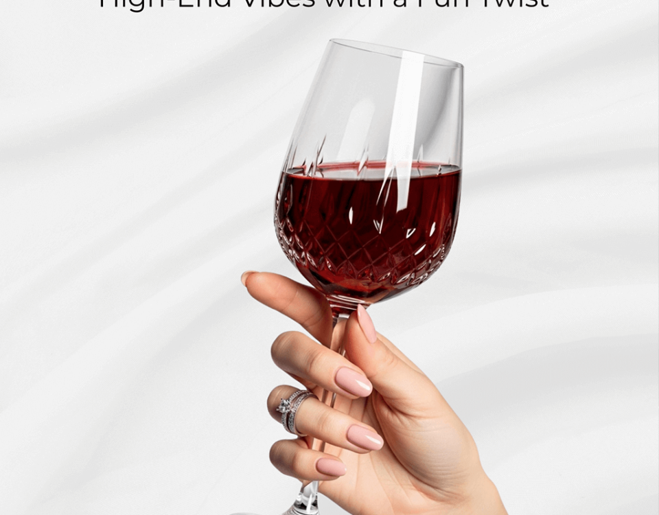 A manicured hand with luxury nails holds a cut-patterned wine glass.